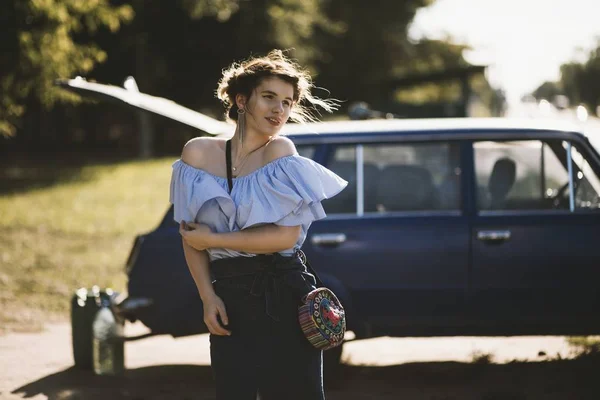 Неглубокий снимок привлекательной женщины-модели в платье без плеча, позирующей рядом с автомобилем — стоковое фото