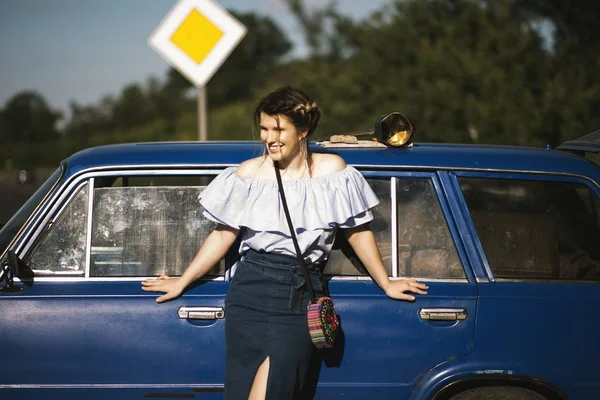 Foco raso tiro de um modelo feminino atraente em um vestido off-shoulder posando perto de um veículo — Fotografia de Stock