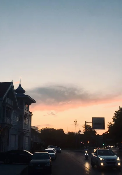 Vertikala skott av bilar på gatan och parkerade nära ett hus under solnedgången — Stockfoto
