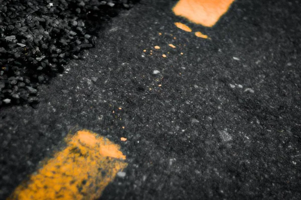 Close shot of a road with yellow stripes near rocks — Stock Photo, Image