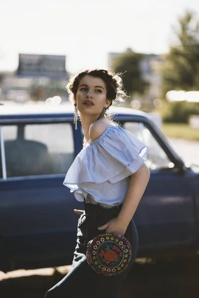一个穿着肩部连衣裙的漂亮女模特站在一辆汽车旁边的浅色镜头 — 图库照片