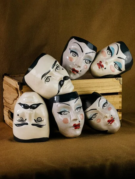 Plan vertical de masques avec visages féminins et masculins près d'une boîte en bois — Photo