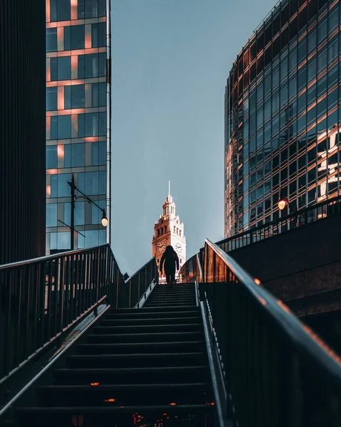 Verticale opname van een persoon die trappen beklimt in de buurt van gebouwen en een klokkentoren — Stockfoto