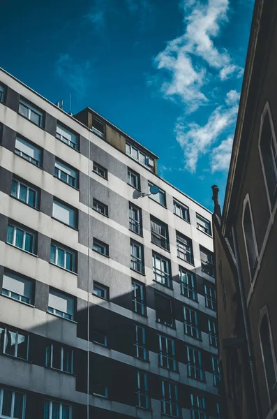 Verticale opname van een grijs-wit gebouw met ramen onder een blauwe lucht — Stockfoto