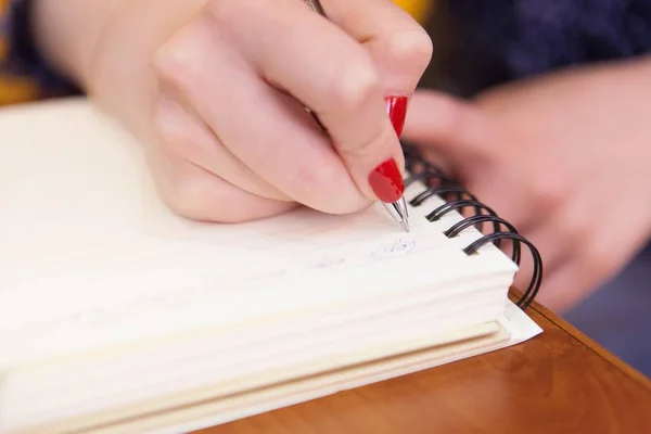 Een close-up van de hand van een vrouw die een pen vasthoudt en iets schrijft in een handboek. — Stockfoto