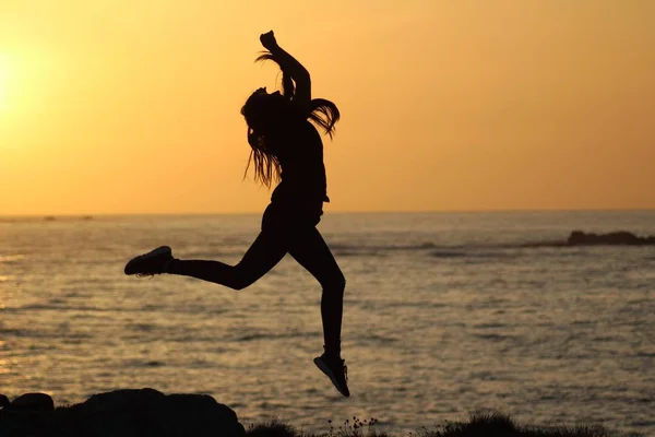Silhouette női jumping közel a tengerhez homályos háttér — Stock Fotó