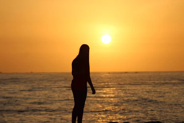 Silhouette of a female standing near the sea with a blurred background — Stock Photo, Image