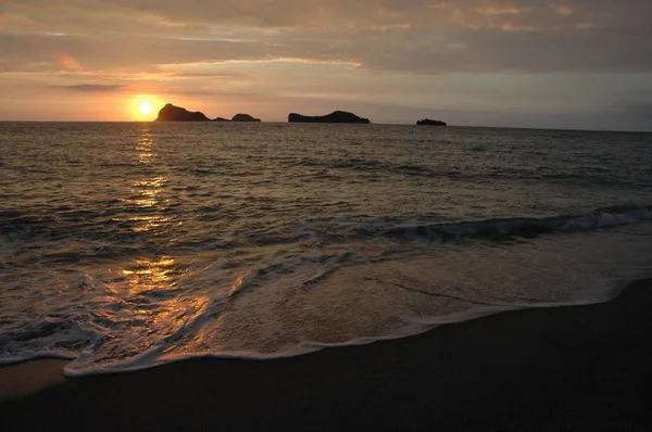 Vue large d'une mer avec des falaises au loin pendant le coucher du soleil — Photo