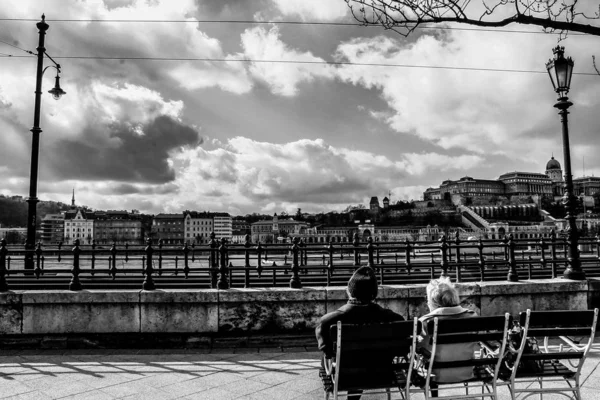 Coppia di anziani seduti su sedie godendo la vista di edifici sotto un cielo nuvoloso — Foto Stock