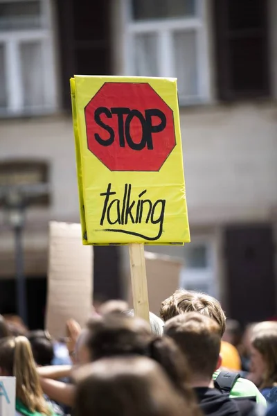Foto vertical de personas sosteniendo un letrero parlante con un fondo borroso — Foto de Stock