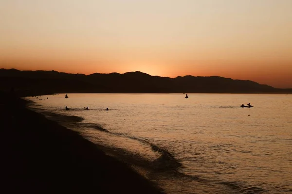 Beautiful shot of people swimming in the water near the shore with a clear sky in the background — Stock Photo, Image