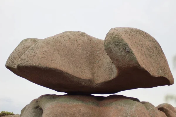 Gros plan d'une grosse roche en équilibre sur une falaise avec un ciel clair en arrière-plan — Photo