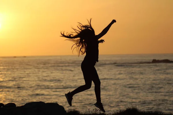 Silhouette einer Frau, die in der Nähe des Meeres springt, mit verschwommenem Hintergrund — Stockfoto