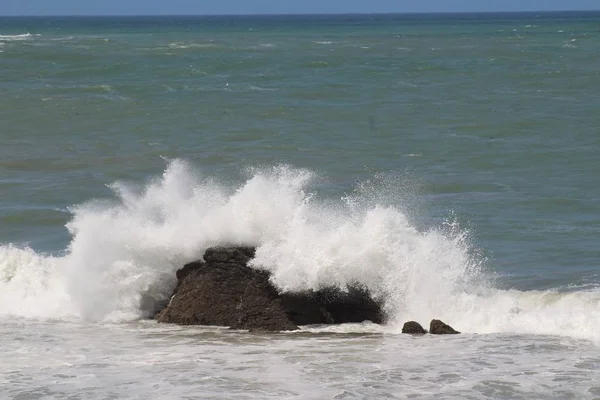 Un disparo cercano de una ola de mar golpeando la roca durante el día — Foto de Stock