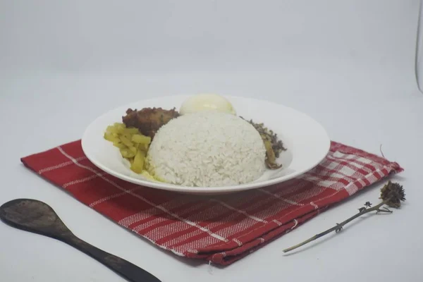 Tahta bir kaşığın yanında yuvarlak bir tabakta pirinç, yumurta ve sebze içeren bir yemeğin yakın çekimi — Stok fotoğraf