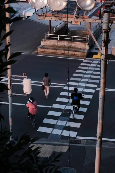 Verticaal schot van mensen, twee van hen rijden fietsen, het oversteken van de straat — Stockfoto