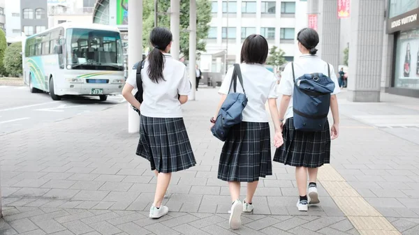 Selektiv bild av tre skolflickor som bär uniform och ryggsäckar gå till skolan-buss — Stockfoto