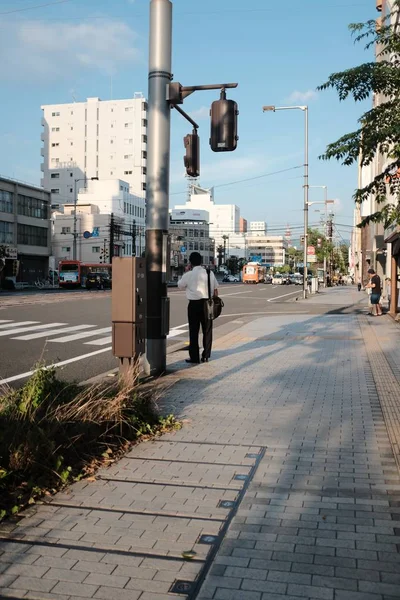 건물이 있는 거리의 신호등 기둥 근처에 서 있는 비즈니스 의류를 입은 남성 — 스톡 사진