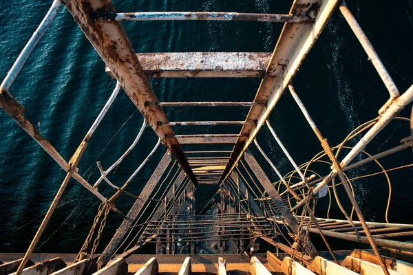 Estremamente vecchia e lacerata scala che scende verso il mare ondulato partendo da un vecchio ponte — Foto Stock