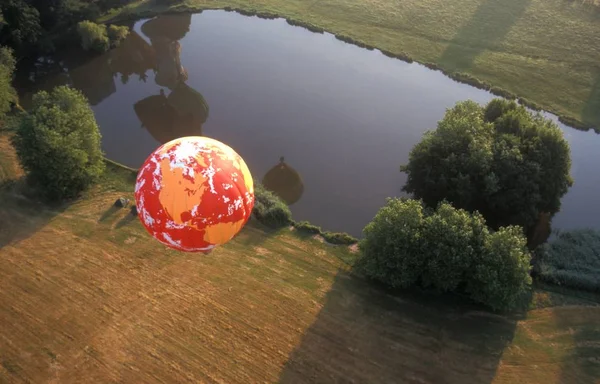 Lotnicze Strzał Czerwonego Balonu Powietrza Nad Suchym Trawiastej Pola Pobliżu — Zdjęcie stockowe