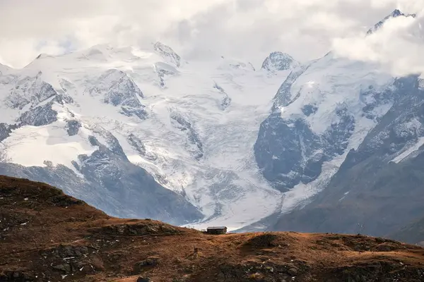 Hermosa foto de una casa en el borde del acantilado con montañas nevadas en el fondo — Foto de Stock