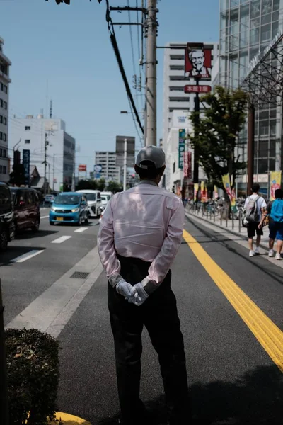 장갑을 끼고 있는 남성과 자동차와 건물이 있는 거리 근처에 서 있는 모자 — 스톡 사진