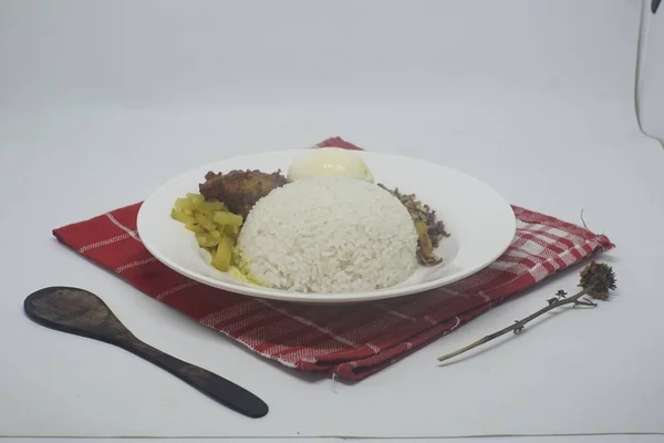 Tahta bir kaşığın yanında yuvarlak bir tabakta pirinç, yumurta ve sebze içeren bir yemeğin yakın çekimi — Stok fotoğraf