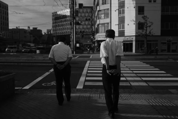 두 명의 남성, 그 중 하나는 스트레칭, 건물과 자동차로 둘러싸인 거리를 건너 — 스톡 사진
