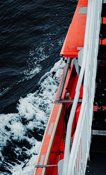 Verticaal schot van een oranje schip met zwarte trappen in een golvende zee — Stockfoto