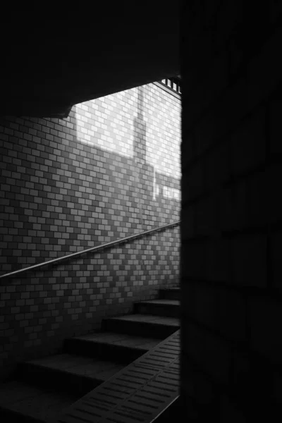 Plan sélectif vertical en niveaux de gris des escaliers avec main courante en acier sur un mur de briques — Photo