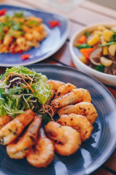 Tiro vertical de plato con gambas y hojas de verduras y un fondo borroso — Foto de Stock