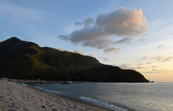 美丽的海滩海岸拍摄，在森林山附近的远处有一条小船 — 图库照片