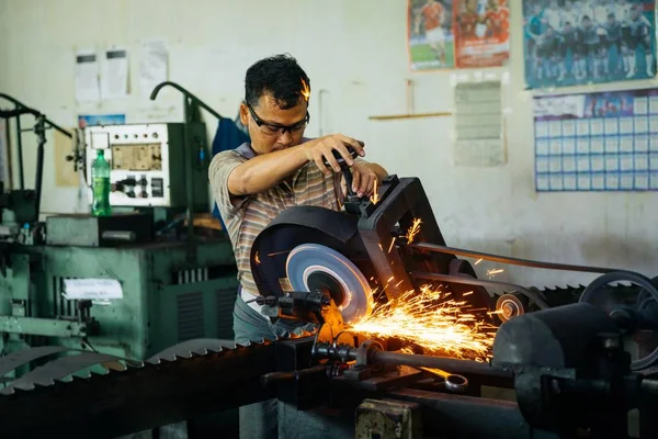 Close shot de um macho trabalhando em uma fábrica de metal com um fundo embaçado — Fotografia de Stock