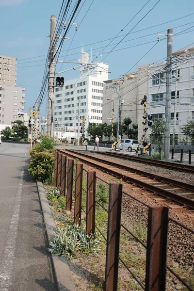 Verticaal schot van bruine rails omringd door gebouwen in een stad onder een blauwe hemel — Stockfoto