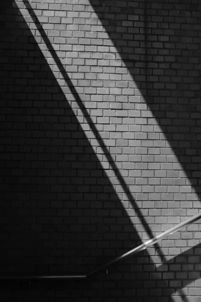 Escala de grises plano vertical de una barandilla de acero en una pared de ladrillo — Foto de Stock