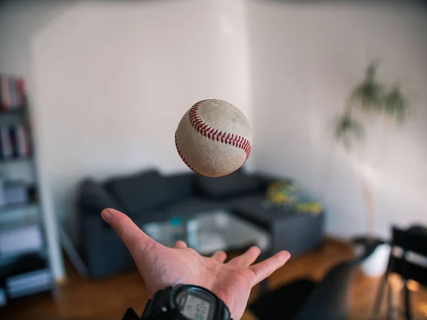 Selective closeup shot of a person tossing a gray baseball into the air — Stock Photo, Image