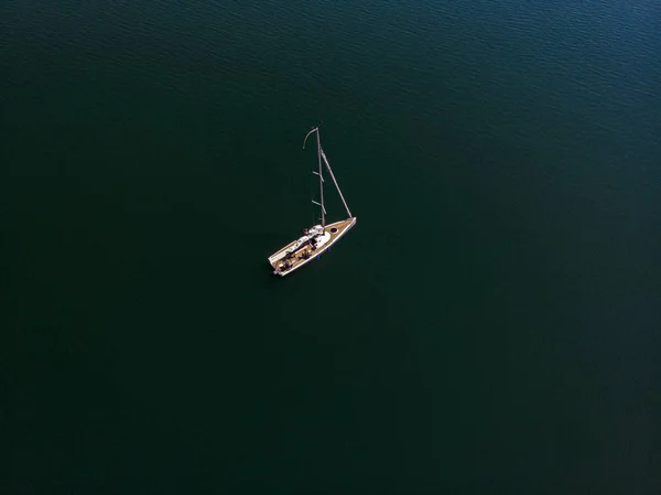 An overhead drone photography of a sailing boat in a beautiful lake on a sunny day