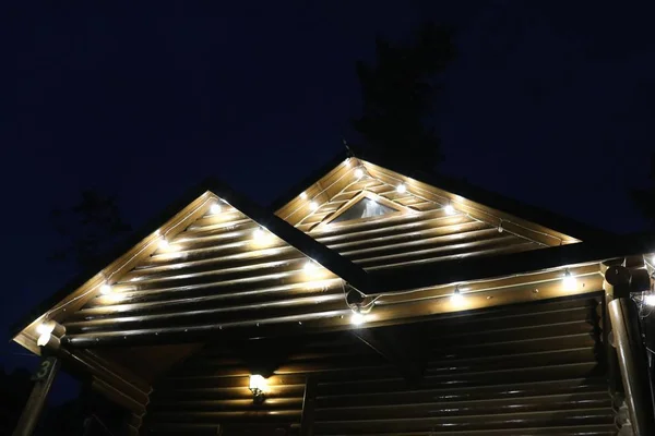 Plan à angle bas des toits triangulaires d'une cabine avec ampoules suspendues la nuit — Photo