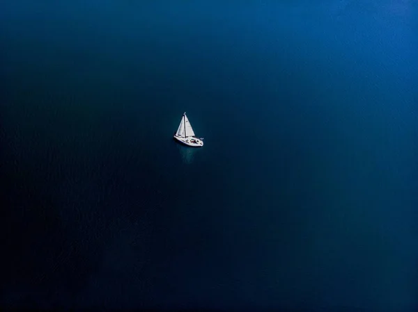 An overhead drone photography of a sailing boat in a beautiful lake on a sunny day