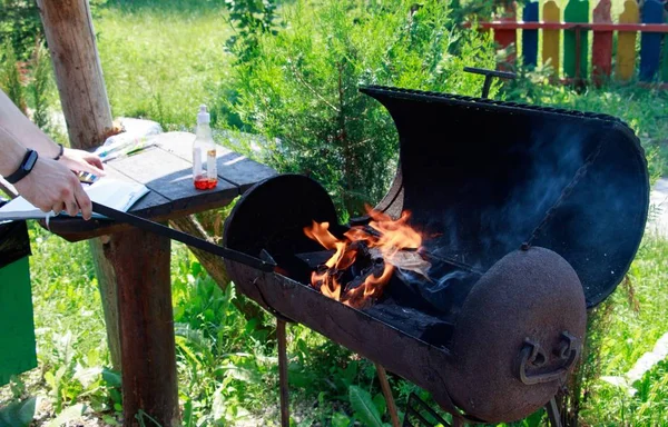 Young male trying to make a fire with charcoal in a barbecue grill to make dinner for the family