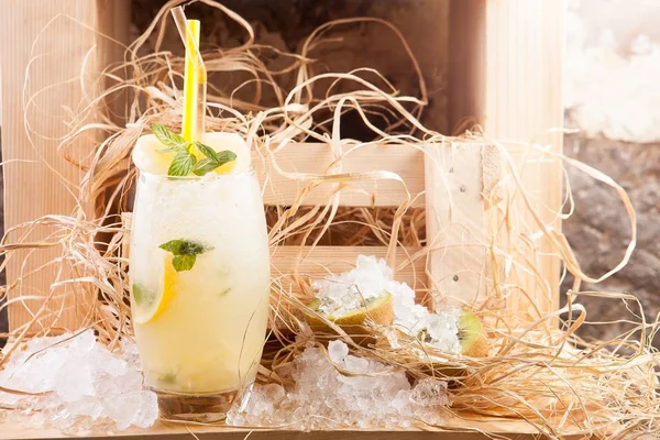 Plan sélectif d'un cocktail au citron avec menthe et kiwi sur le côté recouvert de glace et de décorations — Photo