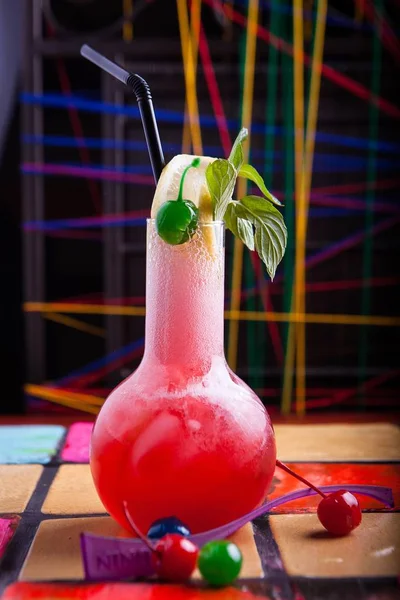 Verticaal schot van een rode cocktail met kersen, citroen en munt met kleurrijke achtergrond textuur — Stockfoto