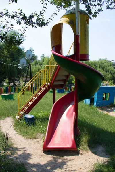 Vertikale Aufnahme einer bunten Spielplatzrutsche mit Drähten und Bäumen im Hintergrund — Stockfoto