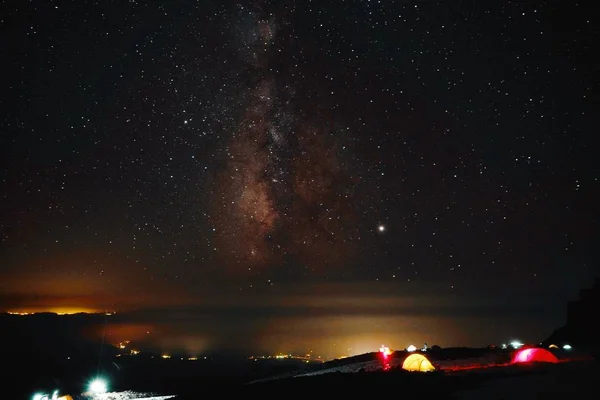 星に満ちた息をのむような空の下の野原で照らされたテントの美しいショット — ストック写真