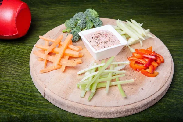 Belo closeup tiro de legumes com um molho em uma tábua de corte com fundo verde — Fotografia de Stock