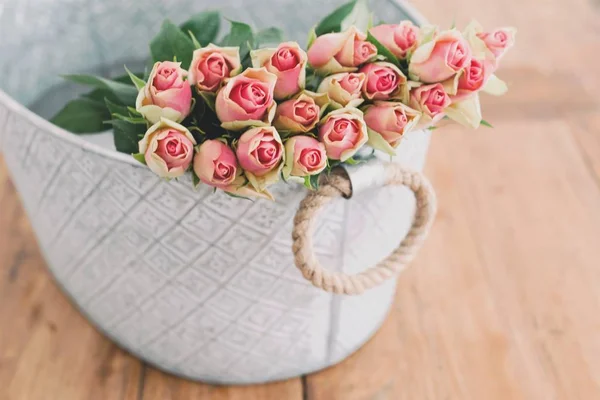 A close shot of pink and yellow flowers in a basket with a blurred background