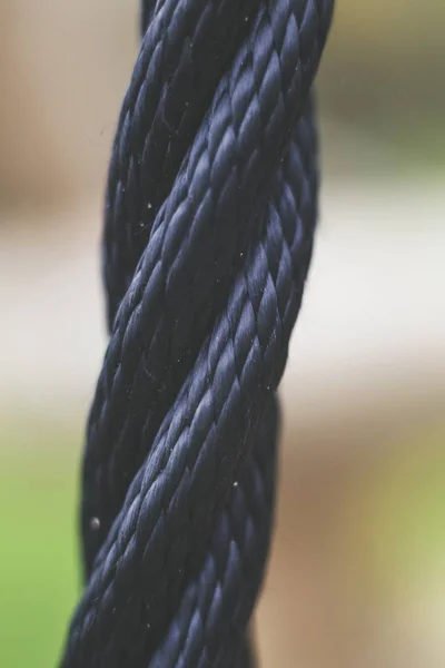 Tiro de close-up seletivo de uma corda preta com um fundo embaçado — Fotografia de Stock