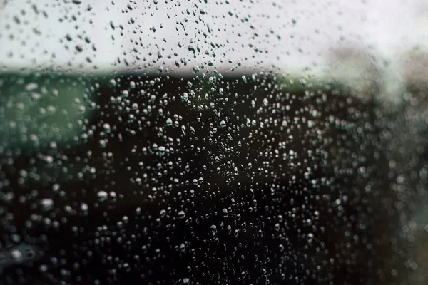 ぼやけた背景を持つガラス窓の雨滴のクローズアップショット — ストック写真