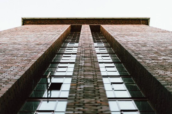 Baixo ângulo tiro um edifício feito de tijolos com janelas e um céu limpo no fundo — Fotografia de Stock