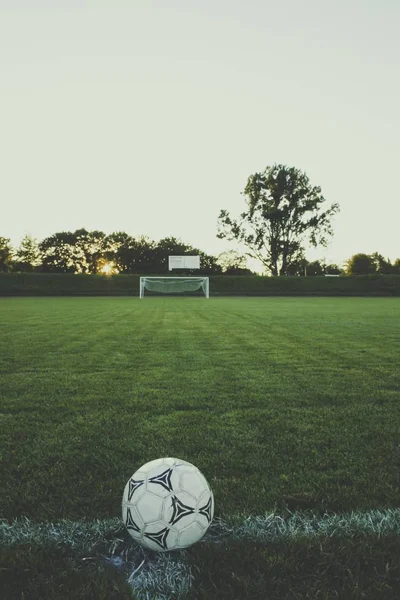 A closeup shot of a black and white football in a football pitch in the evening